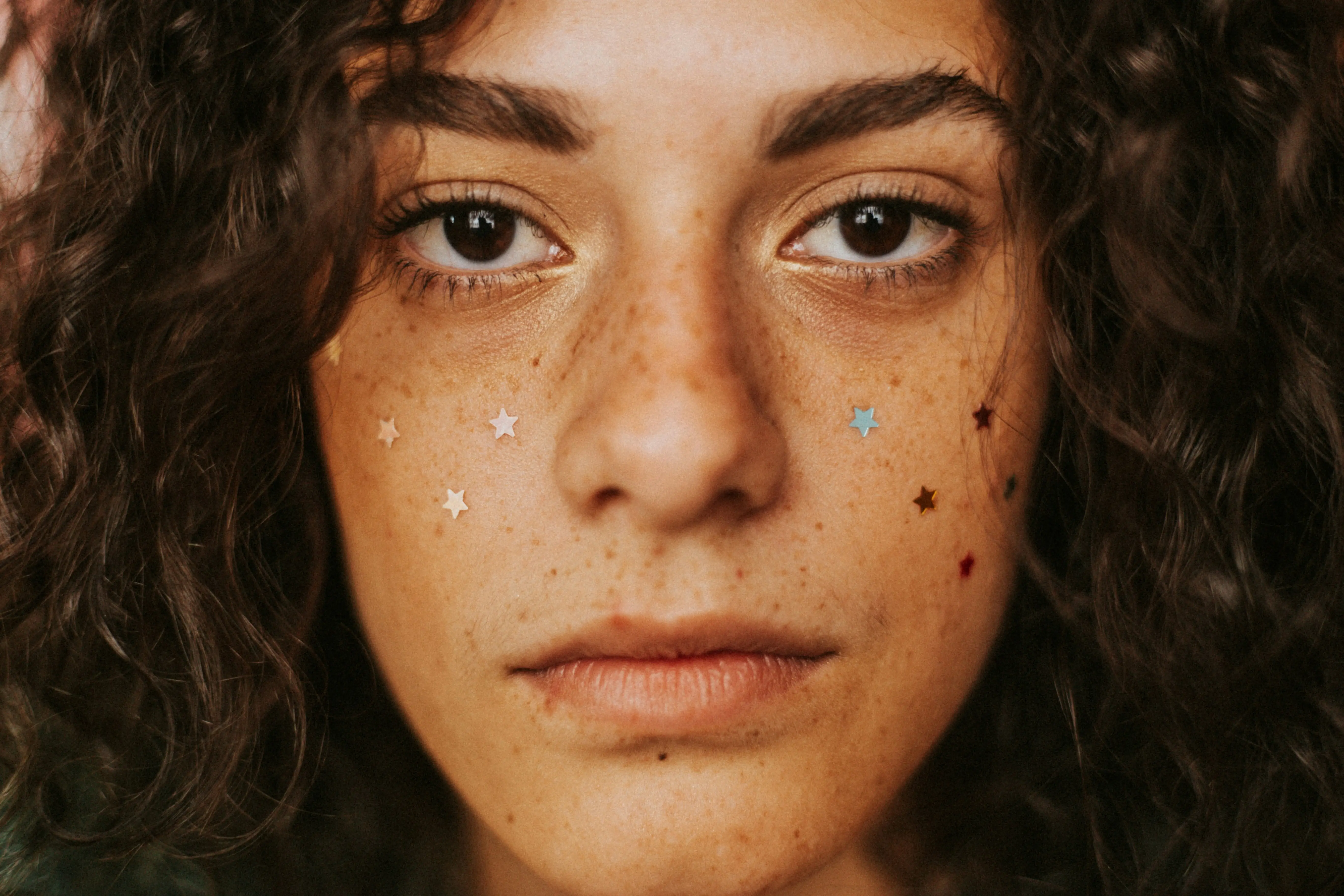 A close-up of a woman with star stickers resembling pimple patches on her face