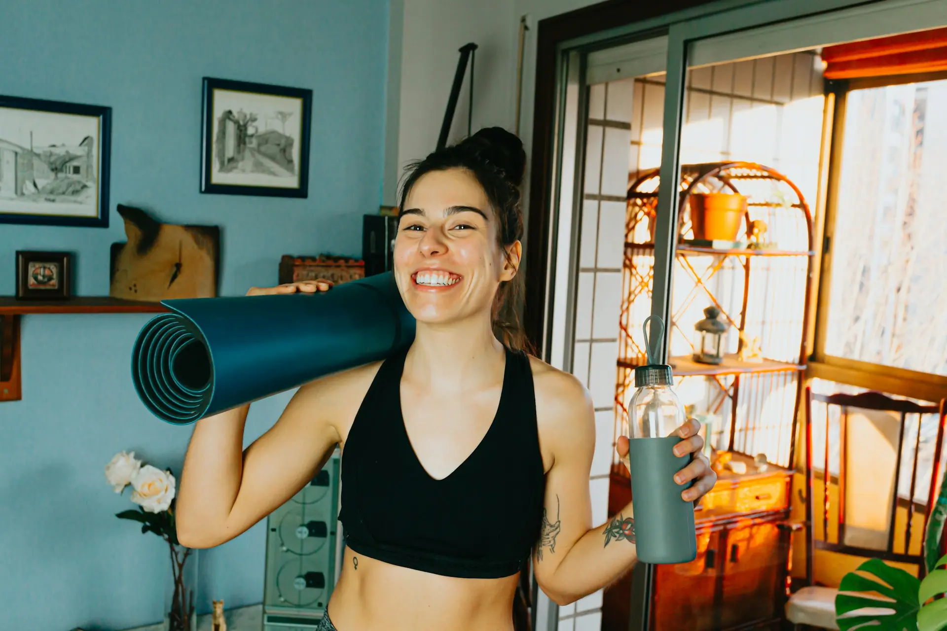 Woman holding blue yoga mat and water bottle