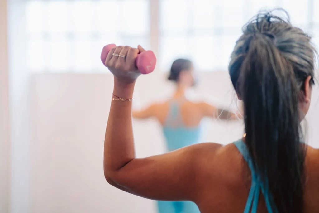 A woman in blue holding a pink dumbbell