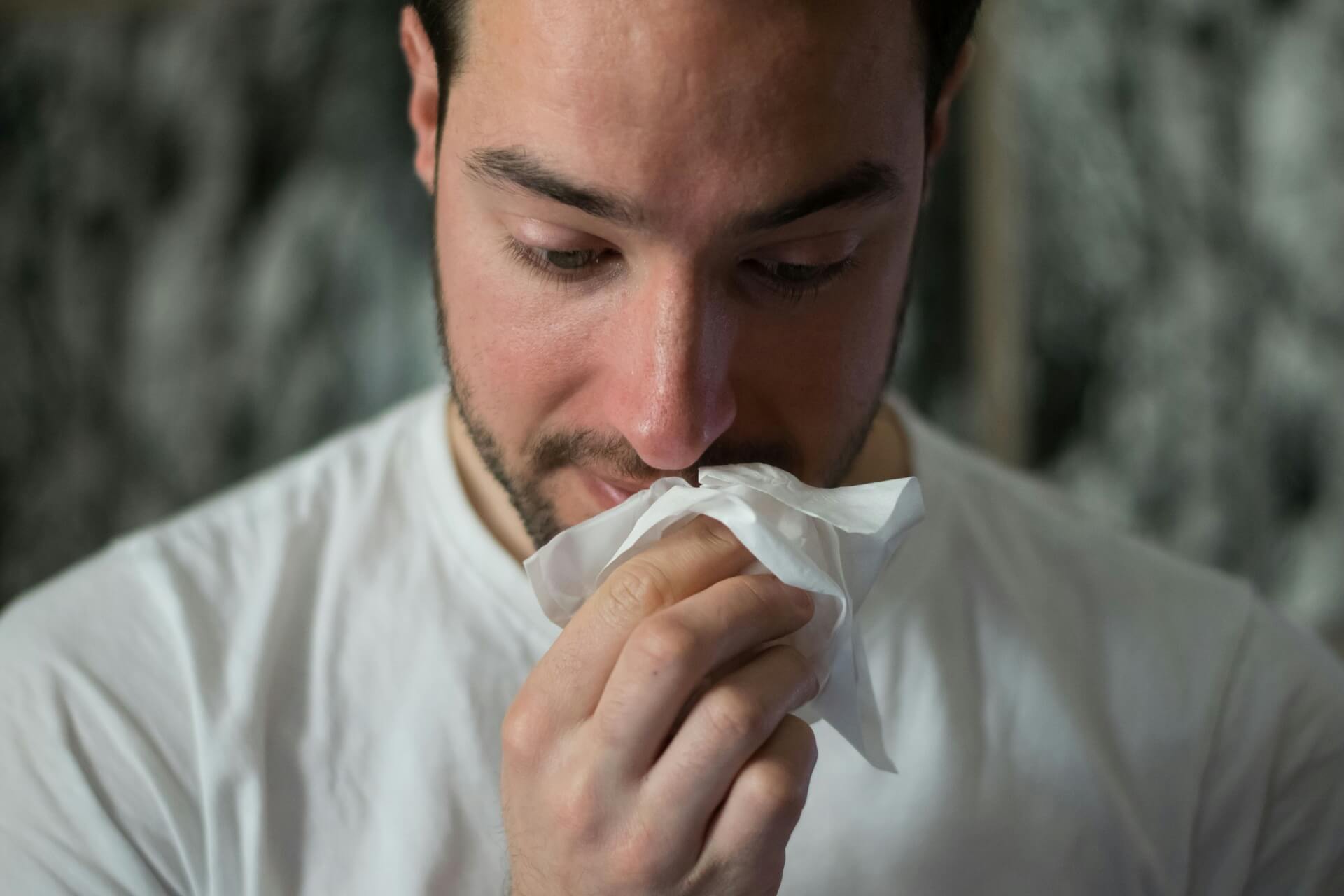 A man using a tissue to wipe his nose