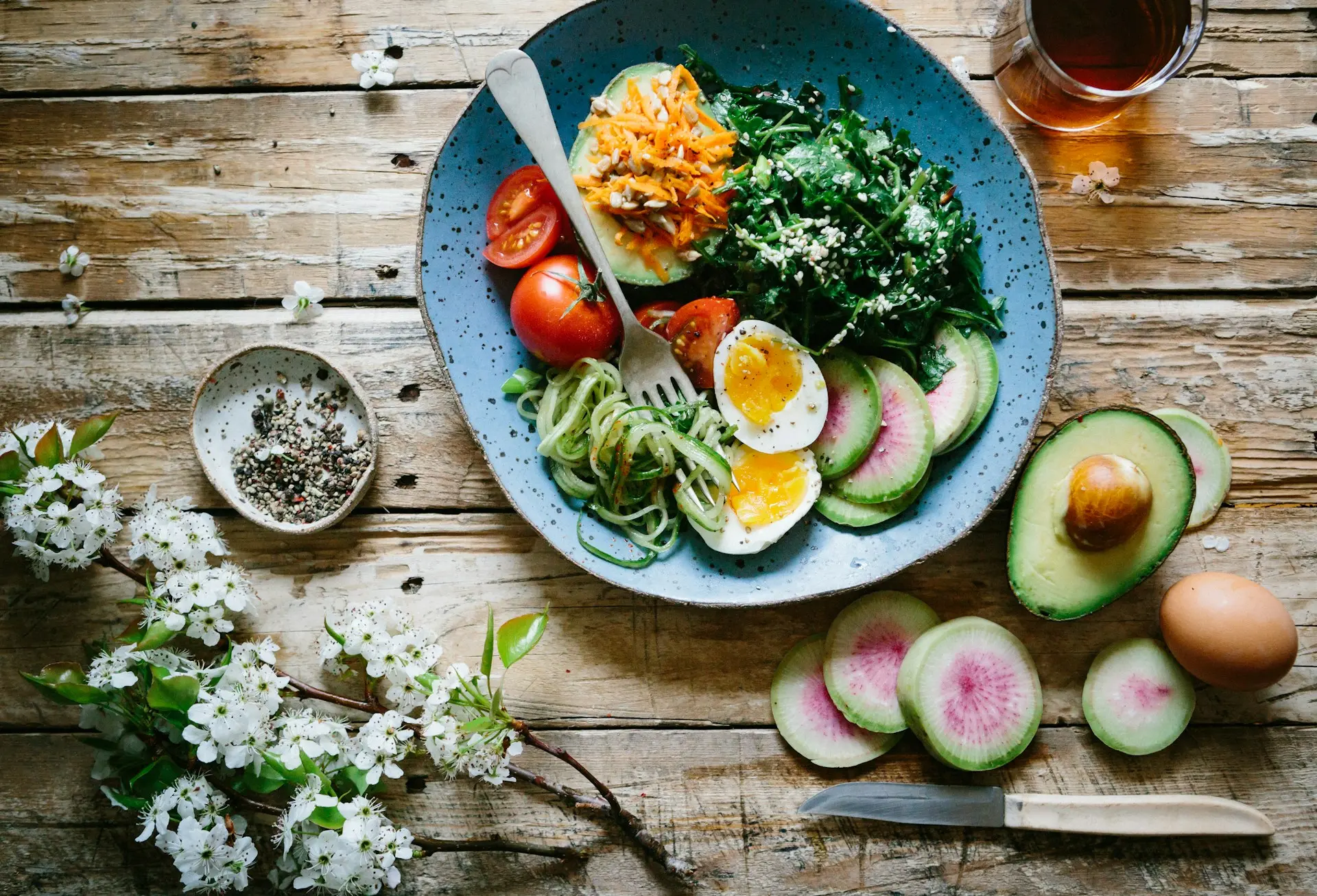 A bowl filled with sliced avocado, eggs, and assorted colorful vegetables, arranged attractively for a healthy meal.
