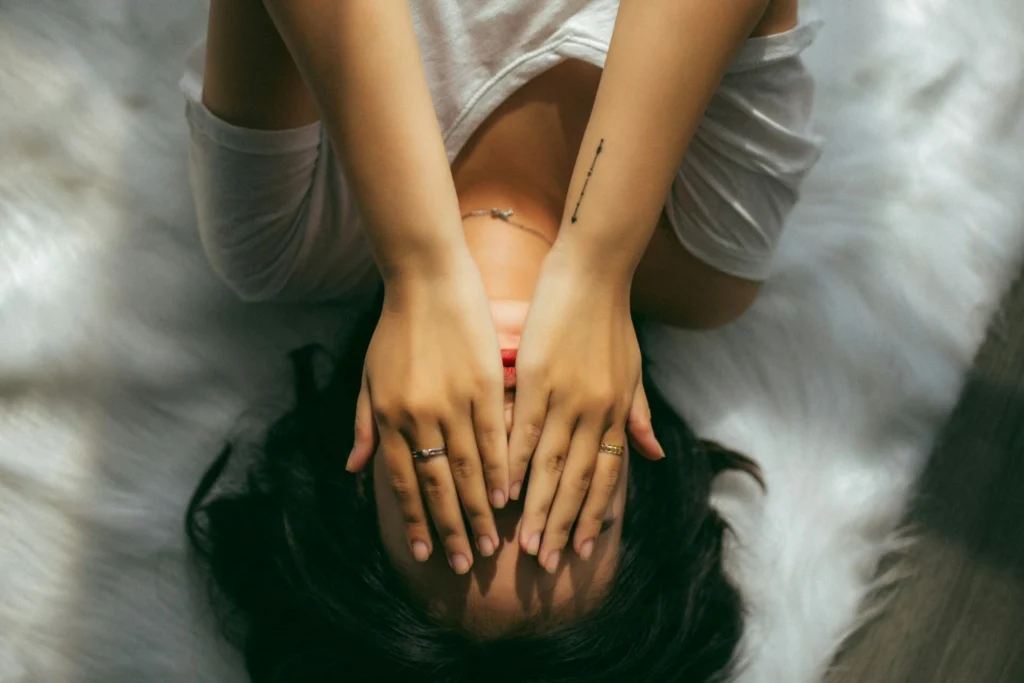 a woman holding her face lying in bed