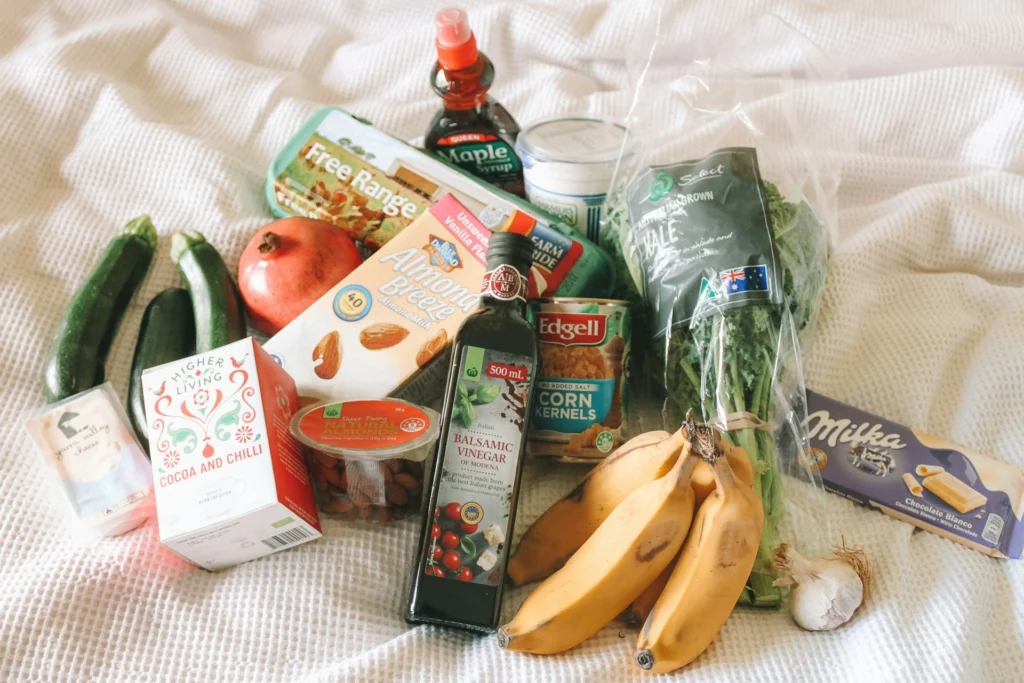 A bed covered with a colorful assortment of groceries, showcasing fresh produce and packaged food items.