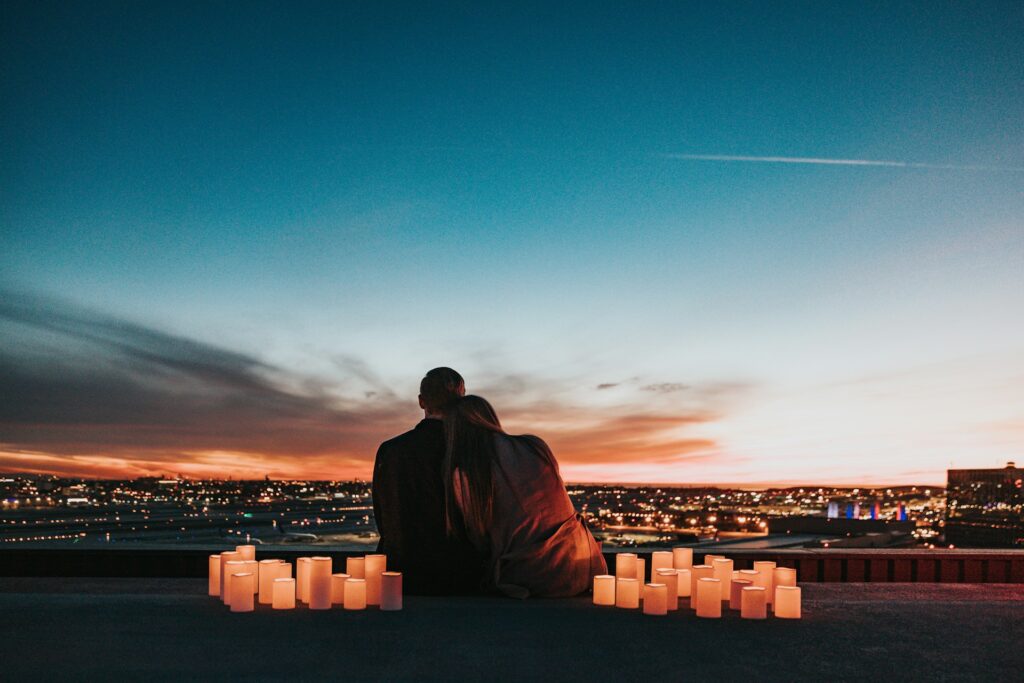 A couple hugging at sunset with candles.