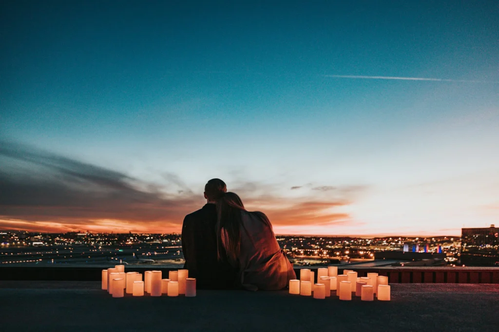A couple hugging at sunset with candles.