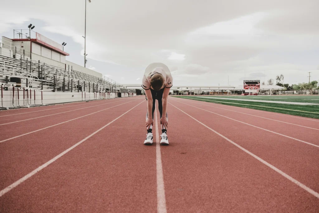 A male runner bending over on a red running track