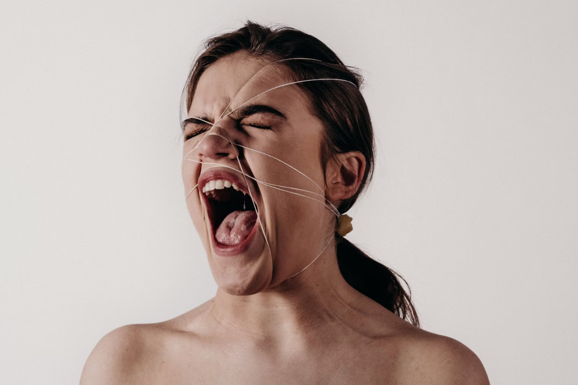 woman with bare shoulders screaming with eyes closed