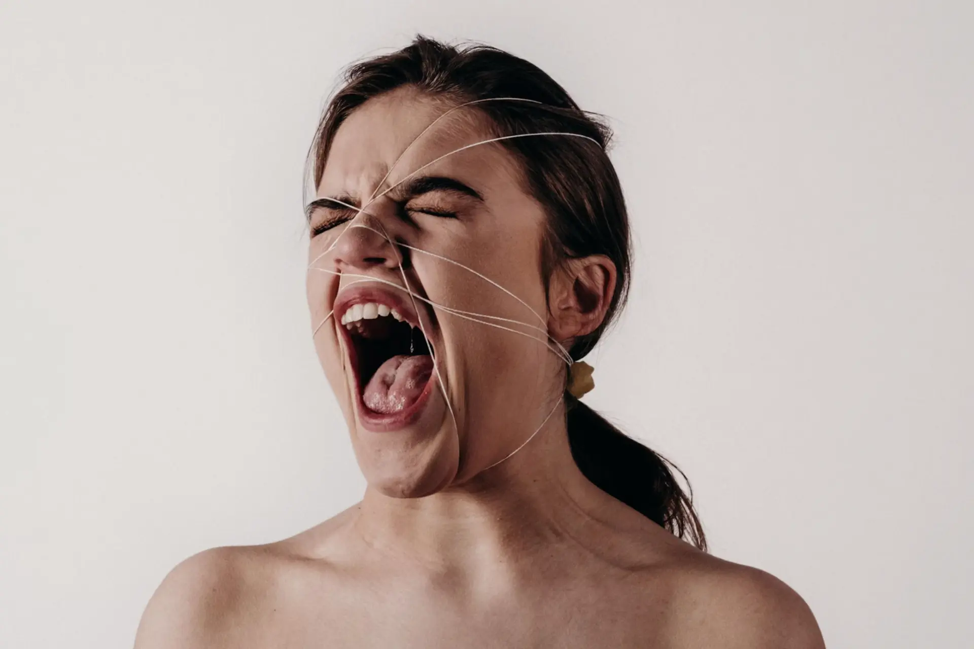 woman with bare shoulders screaming with eyes closed