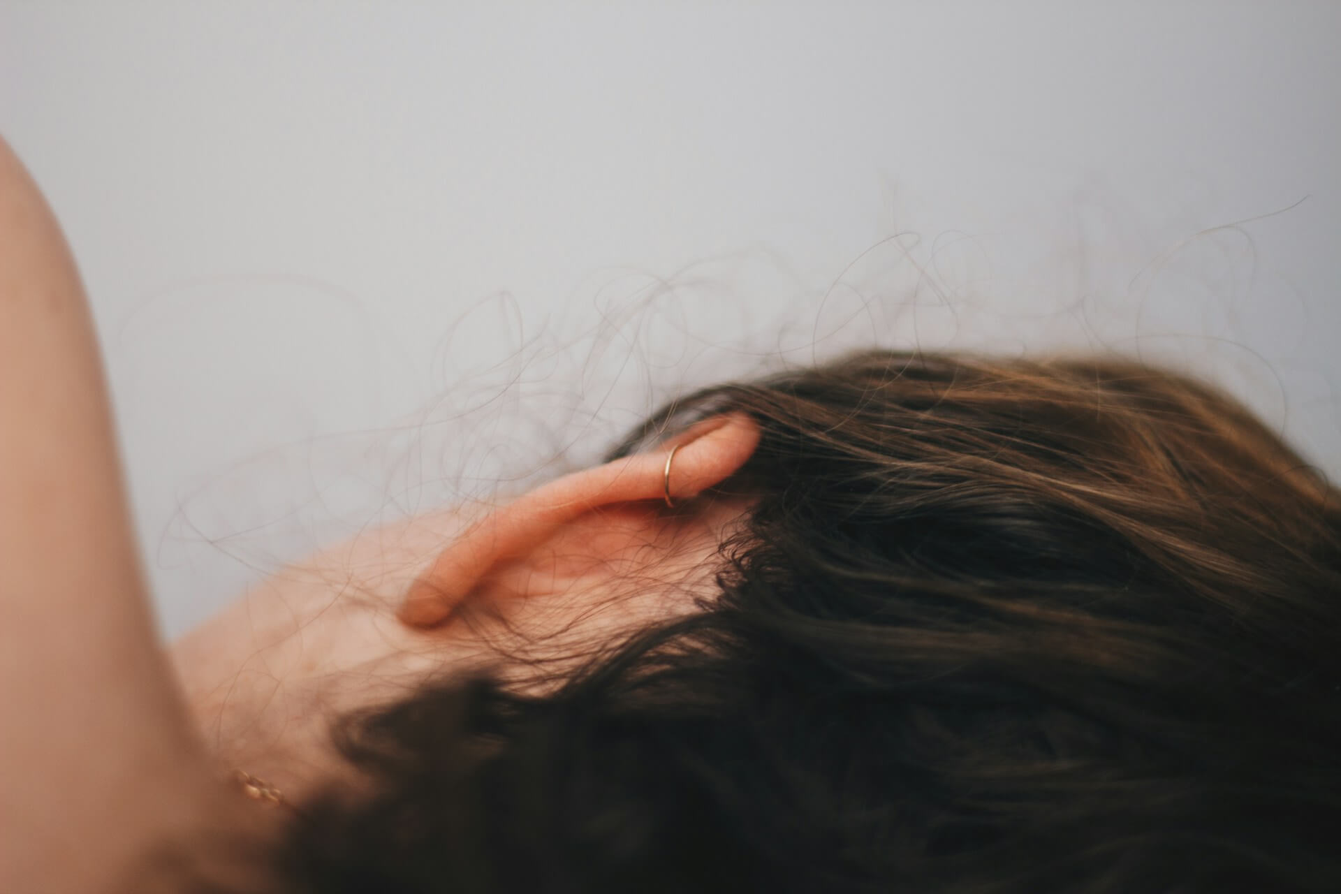 Close-up of a woman's ear and hair while lying down in bed