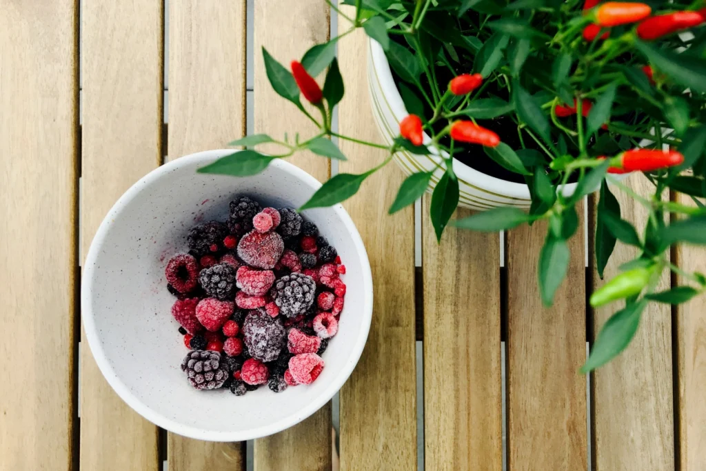 Fresh raspberries and blackberries in a white bowl as an affordable, healthy snack