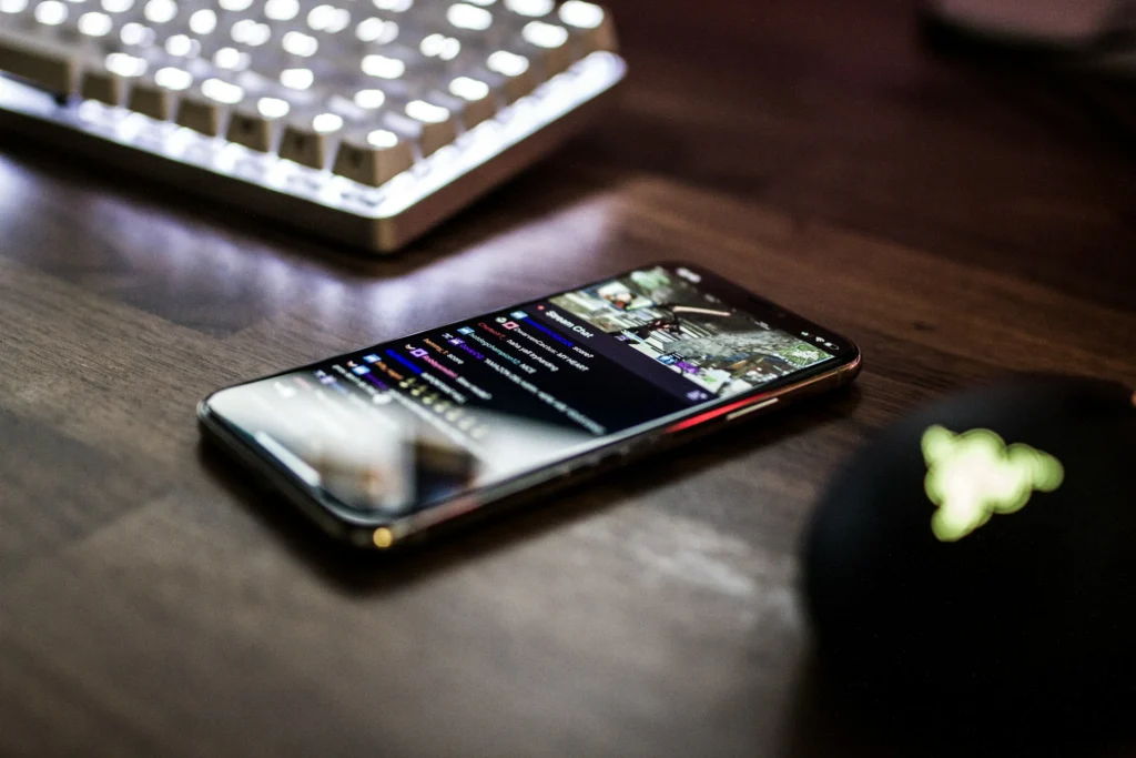 A smartphone rests on a desk beside a computer keyboard, showcasing a modern workspace setup.