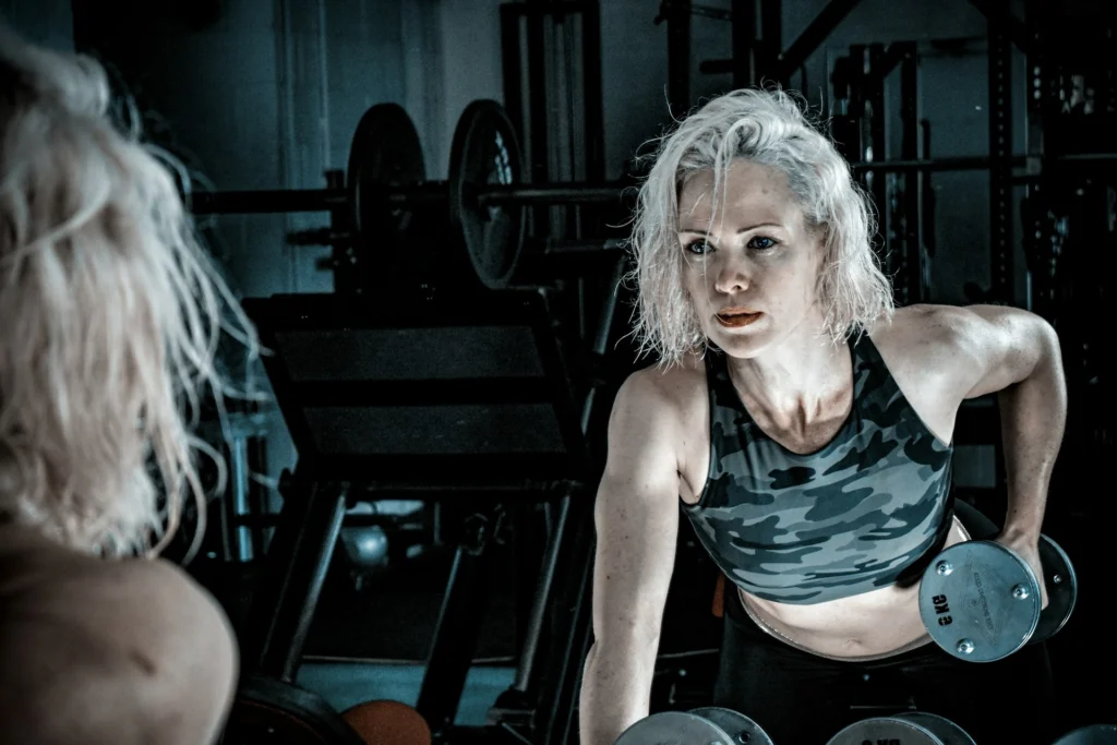 A woman performs a weightlifting exercise in a gym, focusing on strength training and fitness.