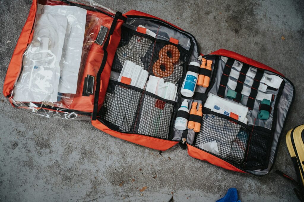 An open medical bag filled with essential supplies like scissors, adhesive tape, and a thermometer for emergency use.