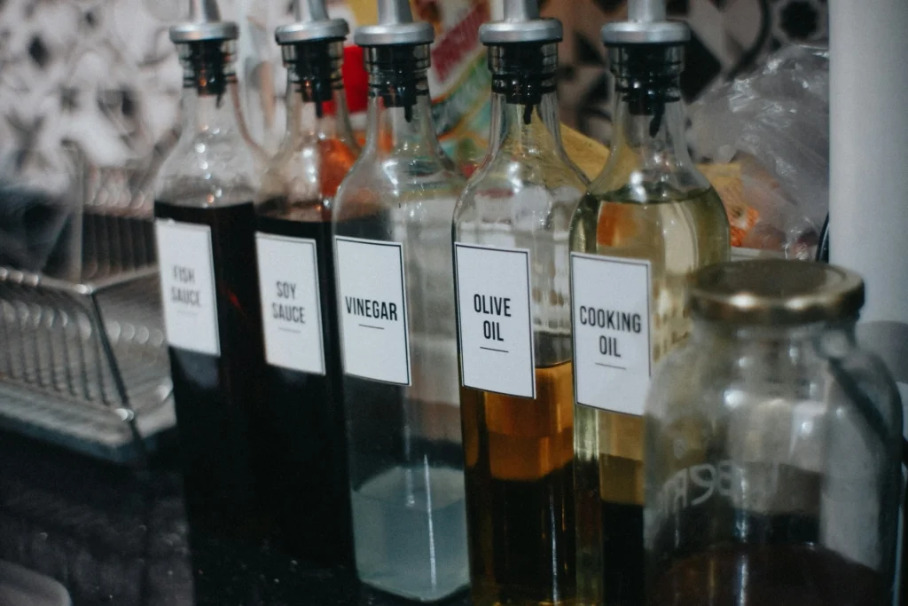 A row of bottles with labels on them sitting on a counter, including vegetable oil