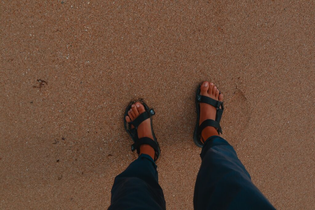 A person wearing hiking sandals on a beach