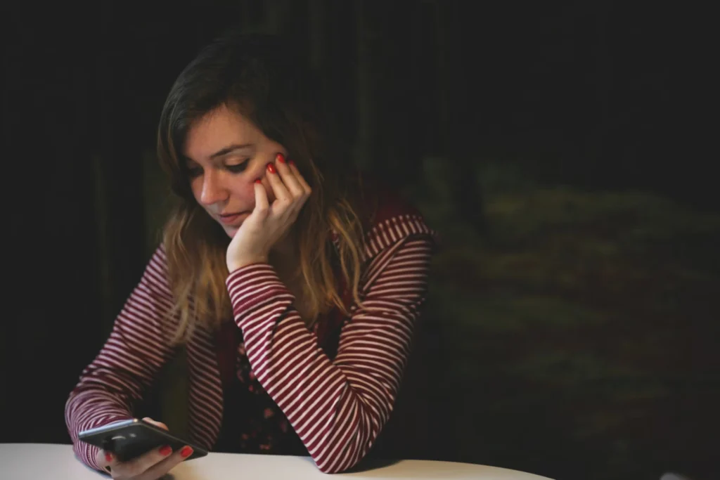serious girl in red and white stripes using phone