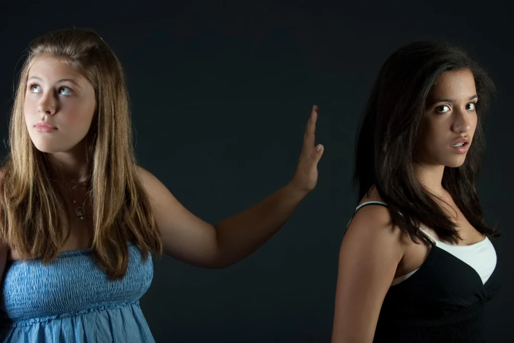 girl in blue holding hand up to girl in black and white