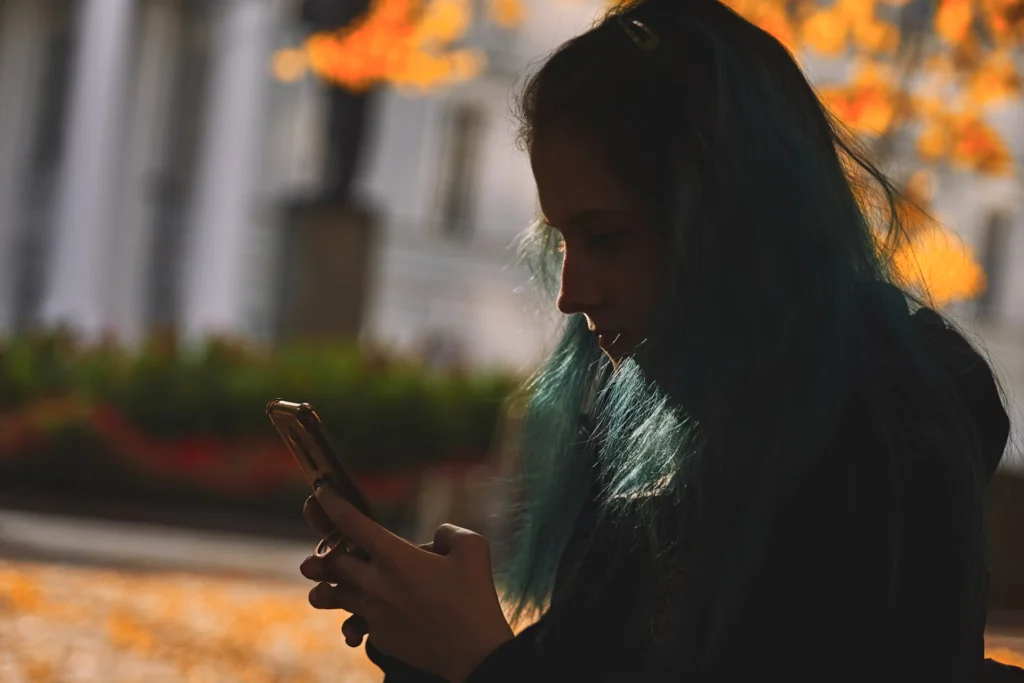 green-haired girl in shadows using phone