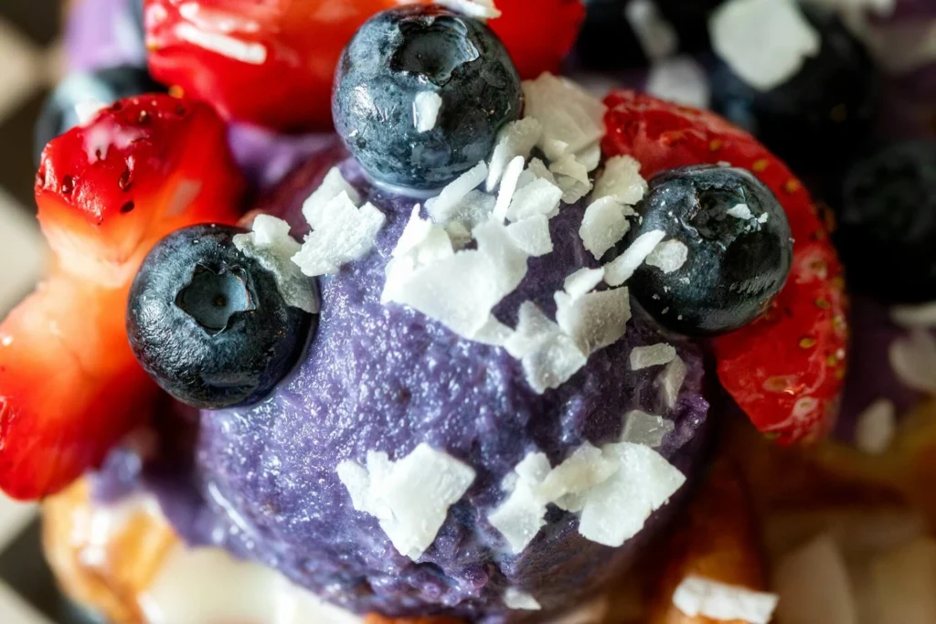 ube halaya topped with blueberries, strawberries and coconut flakes