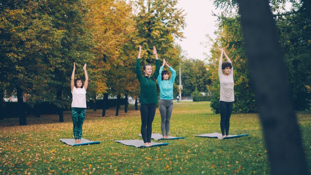 Women practicing yoga poses in a park