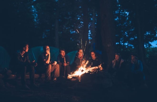 group of people sitting around a camp fire