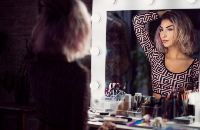 woman confidently looking at herself in the mirror