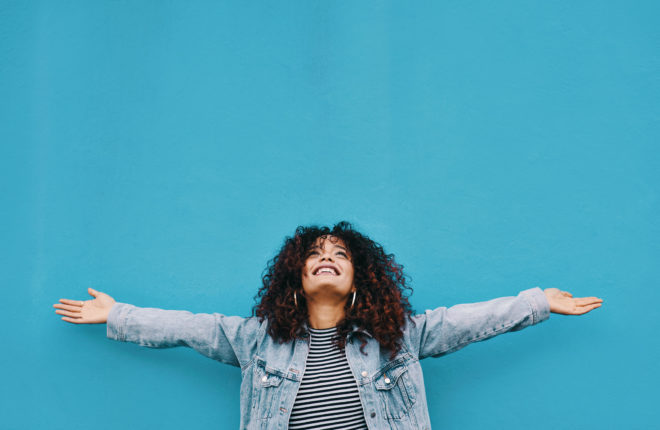 Woman standing in front of blue wall with hands outstretched
