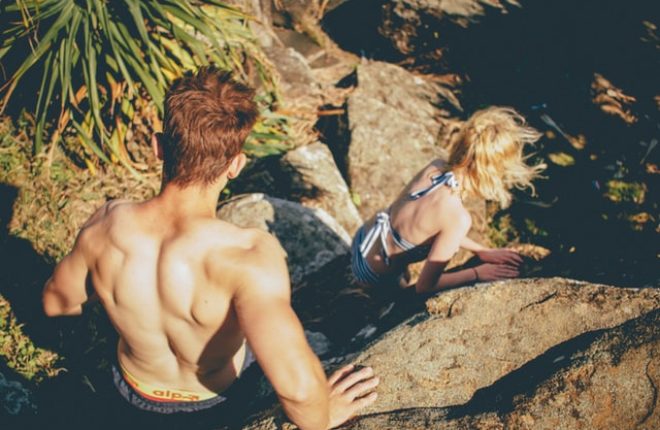 couple climbing down rocks in swimsuits
