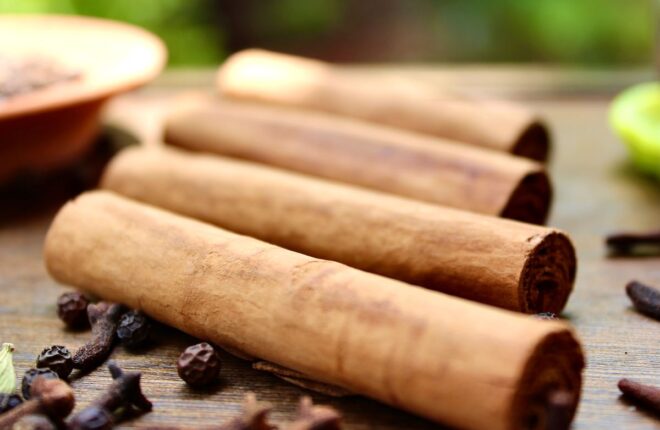 a close up of cinnamon sticks sitting on a wooden table highlighting the health benefits of cinnamon