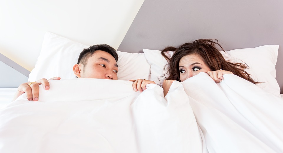 Two people in a relationship seem afraid to leave the bed and can only look at one another with their white duvet pulled up to their noses. Can codependency be healthy?