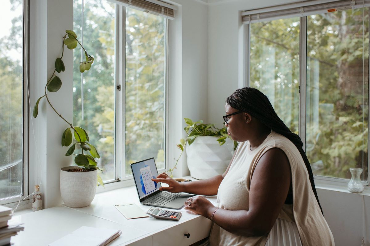 a woman sitting at her desk in front of windows who knows how to make working from home fun
