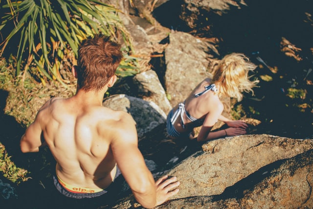 couple climbing down rocks in swimsuits