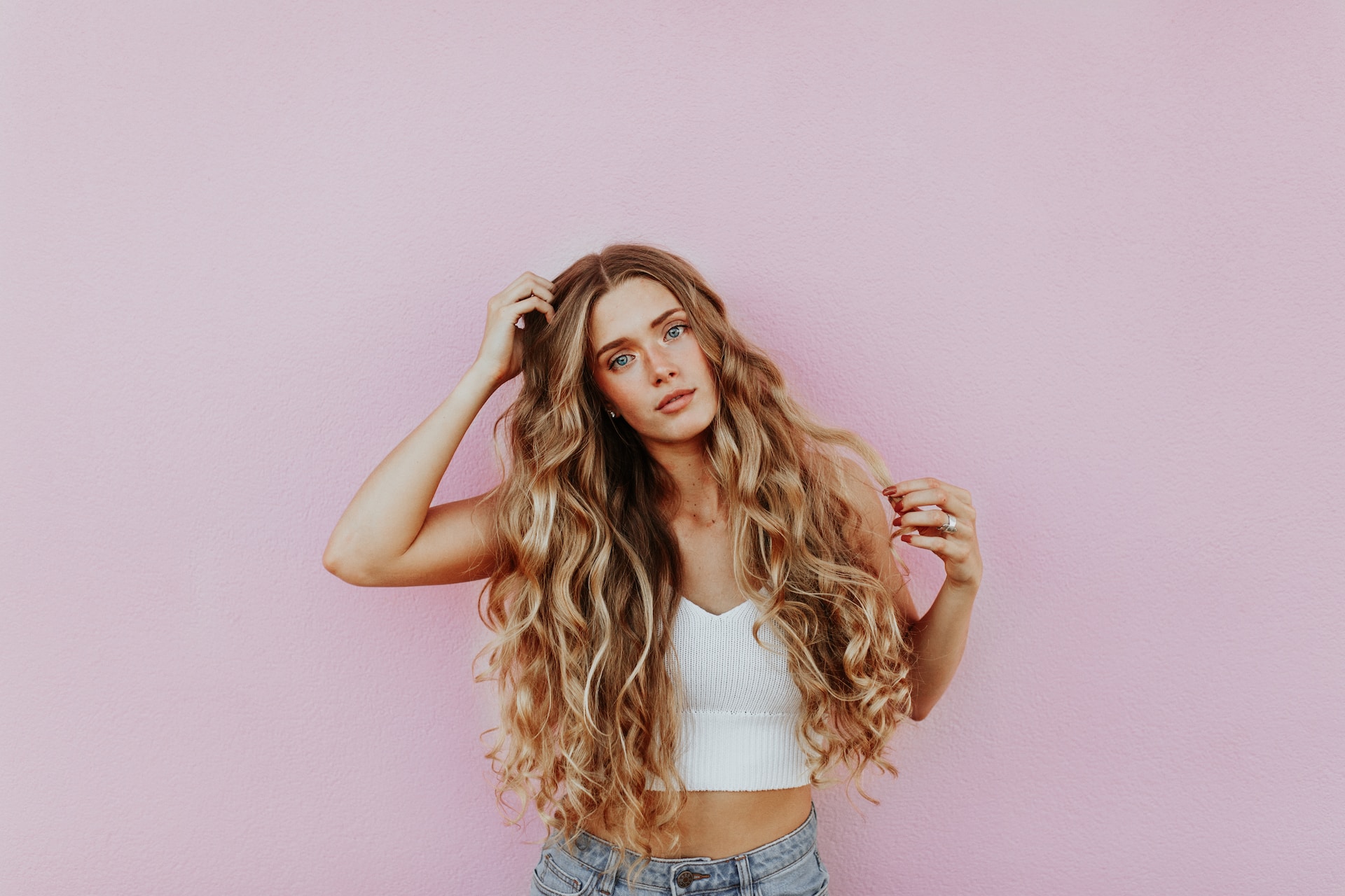 Woman with curly blonde hair in front of a pink wall