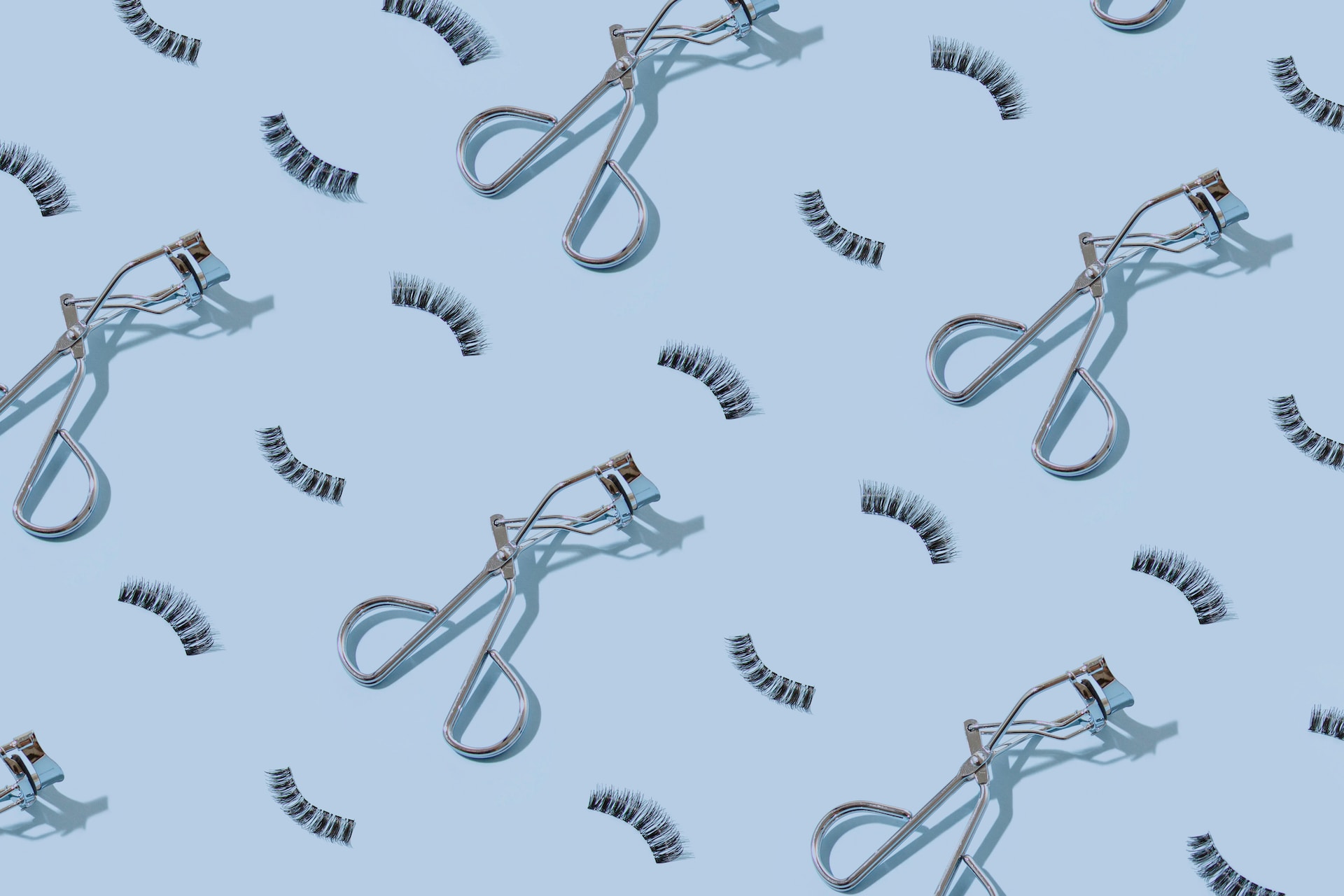 eyelash curlers with lash extensions on a blue background