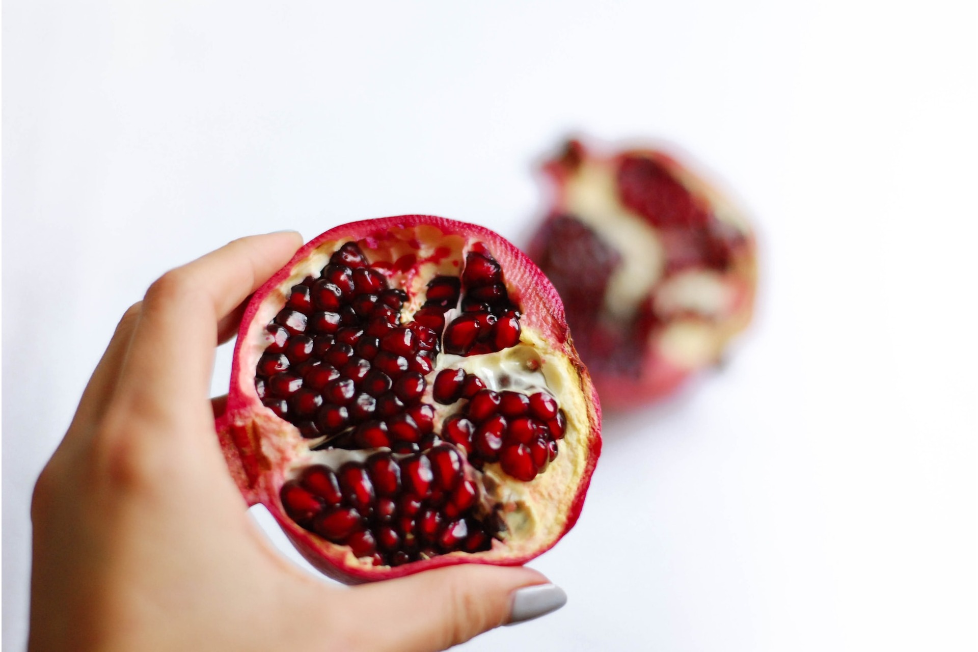 A woman's hand with an open pomegranate - benefits of pomegranate