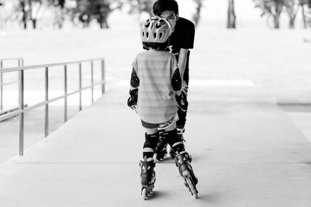 A teenager teaching a kid how to rollerblade