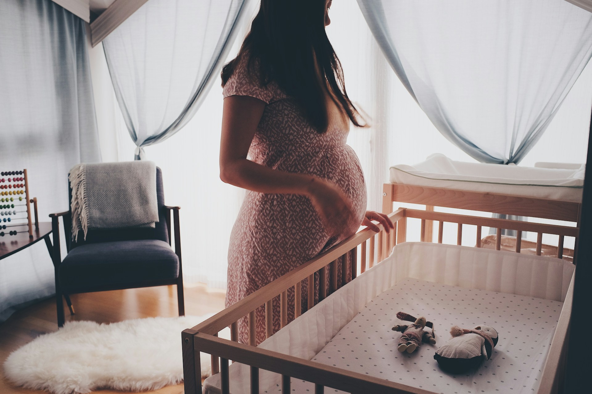 A pregnant woman standing in a baby nursery