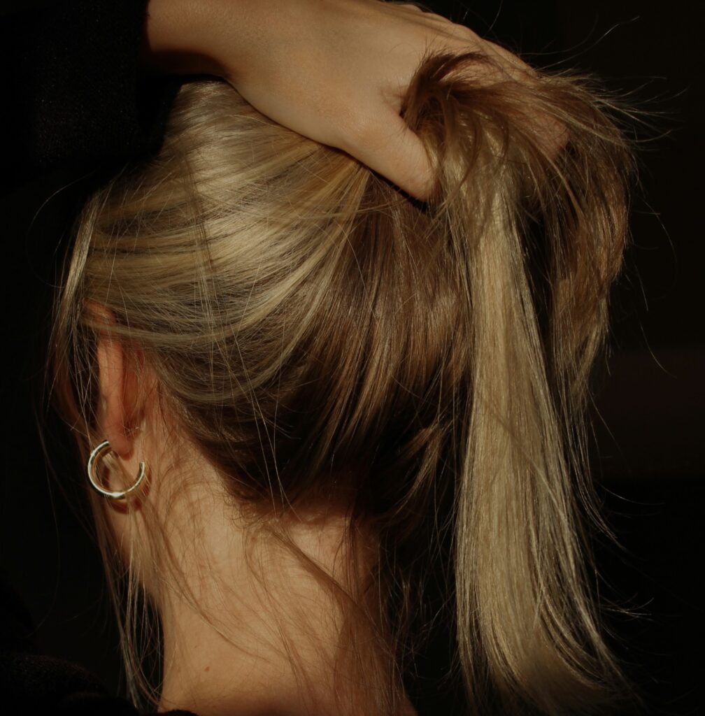 Woman holding her hair in a ponytail formation. 