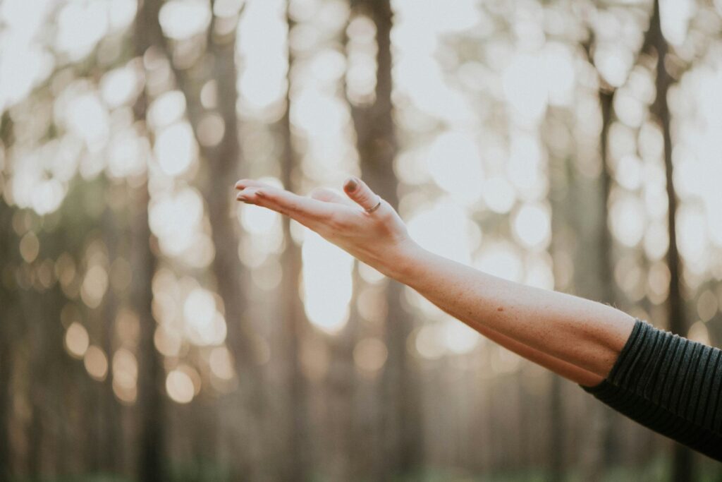 An extended arm and hand against a background of blurred trees.