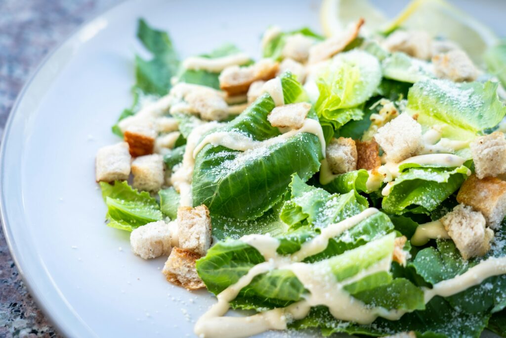 A bowl of Caesar salad covered in dressing.