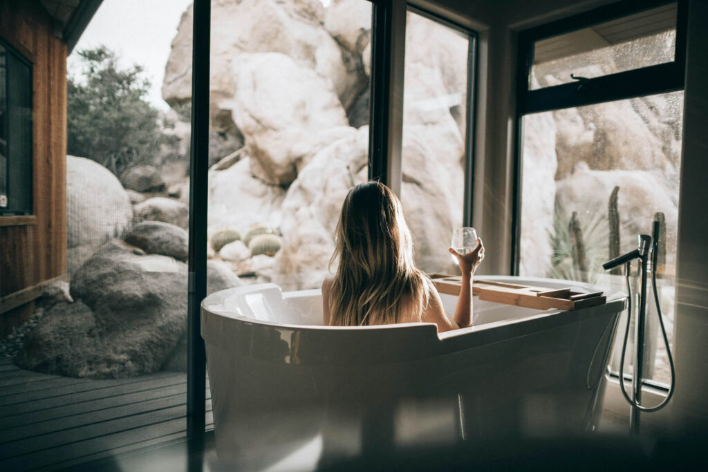 person in bath holding glass