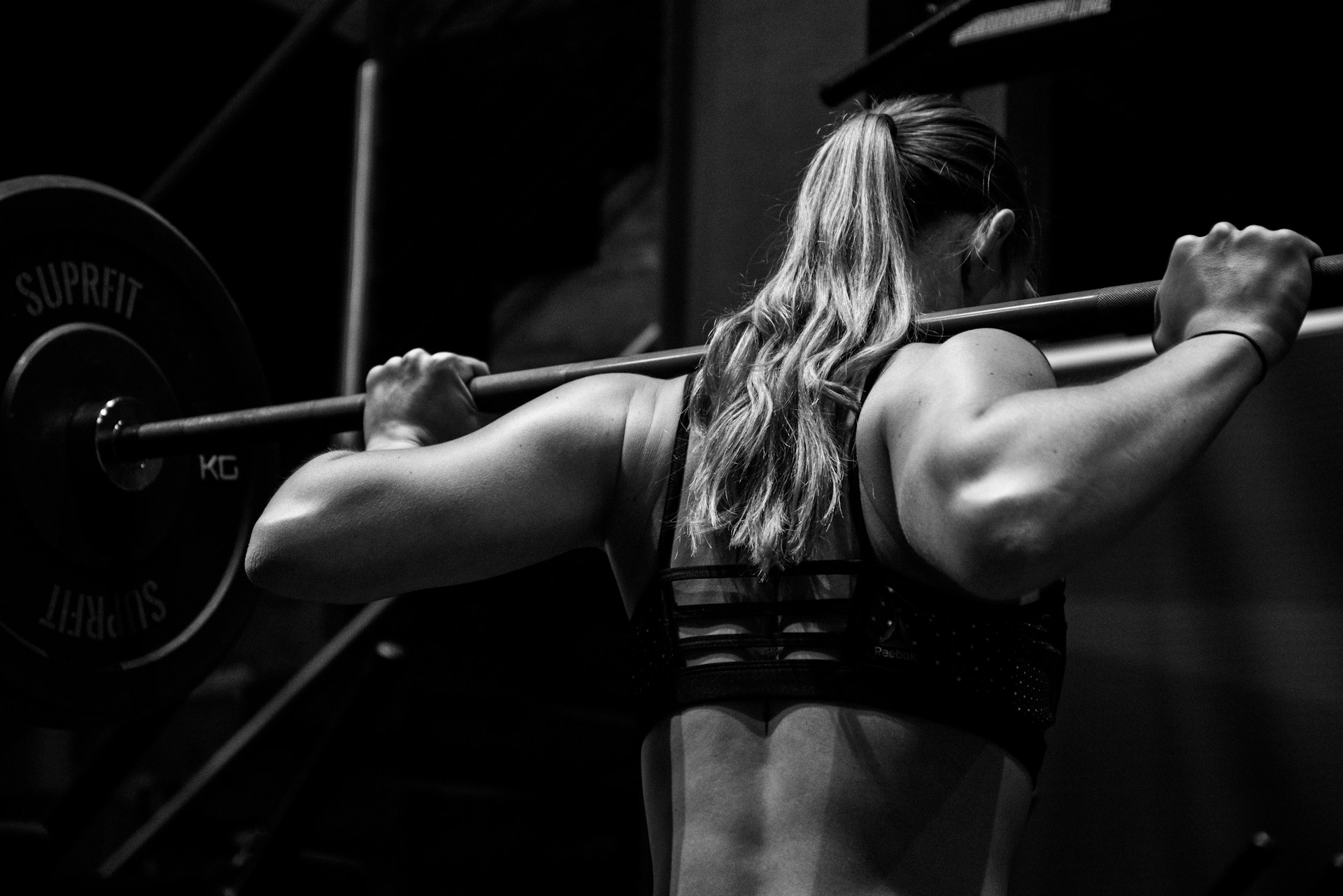 A woman who is carb cycling lifting weights in the gym.