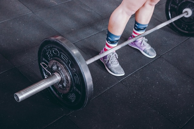 A girl standing next to weights at the gym