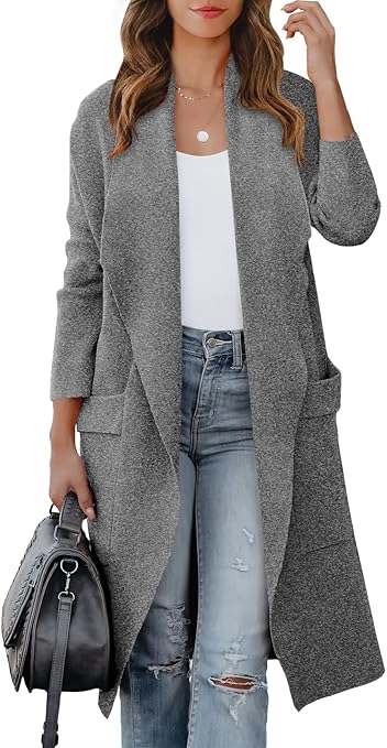 A woman in ripped jeans and a white shirt stands against a white background while wearing a gray cardigan jacket with a gray purse.