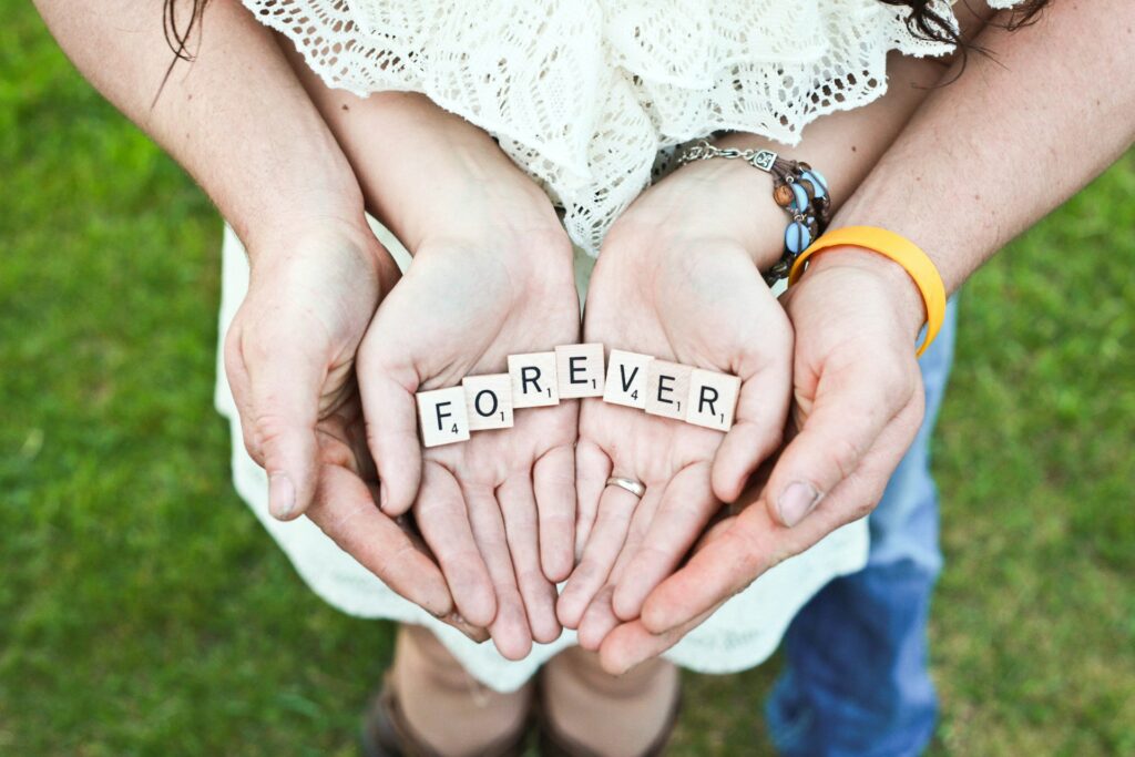 A man and woman cup their hands around Scrabble letters that spell out "Forever."