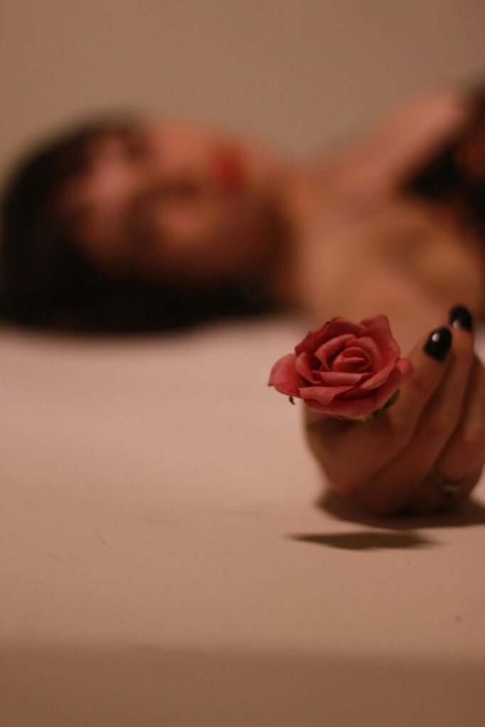 A girl with black nail polish holding a rose 