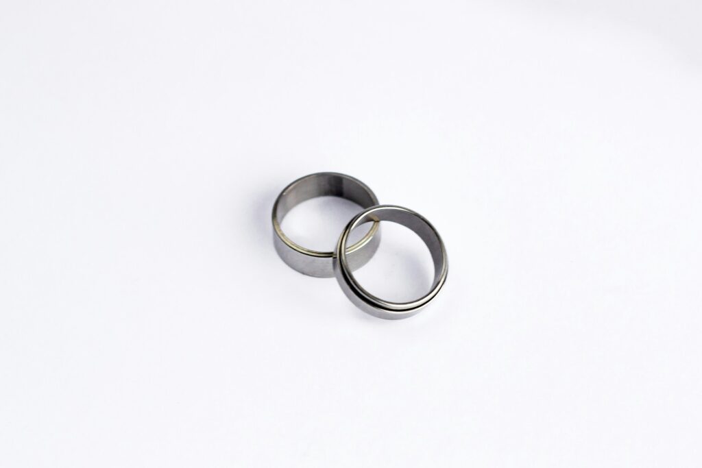 Two silver rings sit on top of each other below the camera on a white surface.