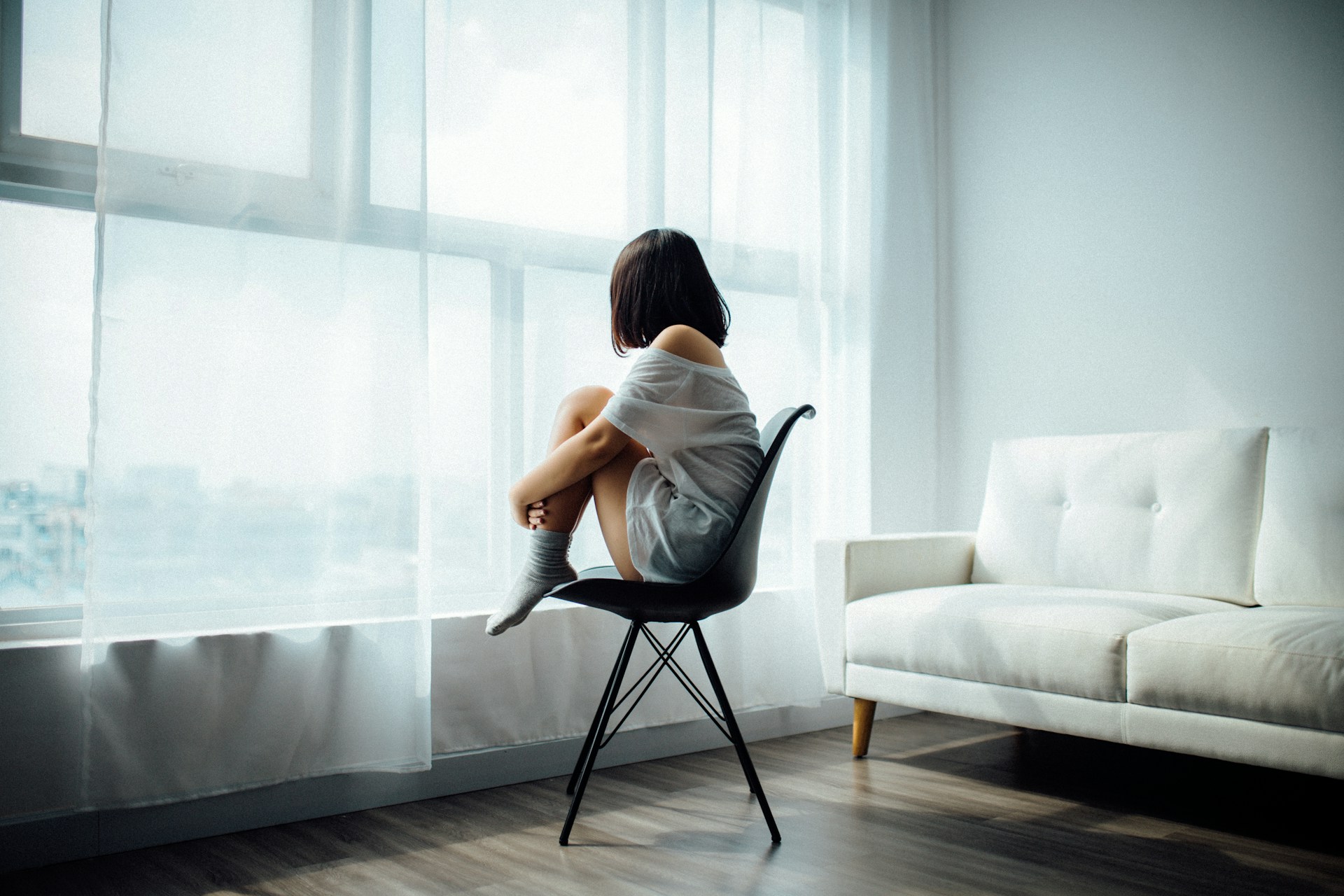 A woman with body dysmorphia sitting on a chair.