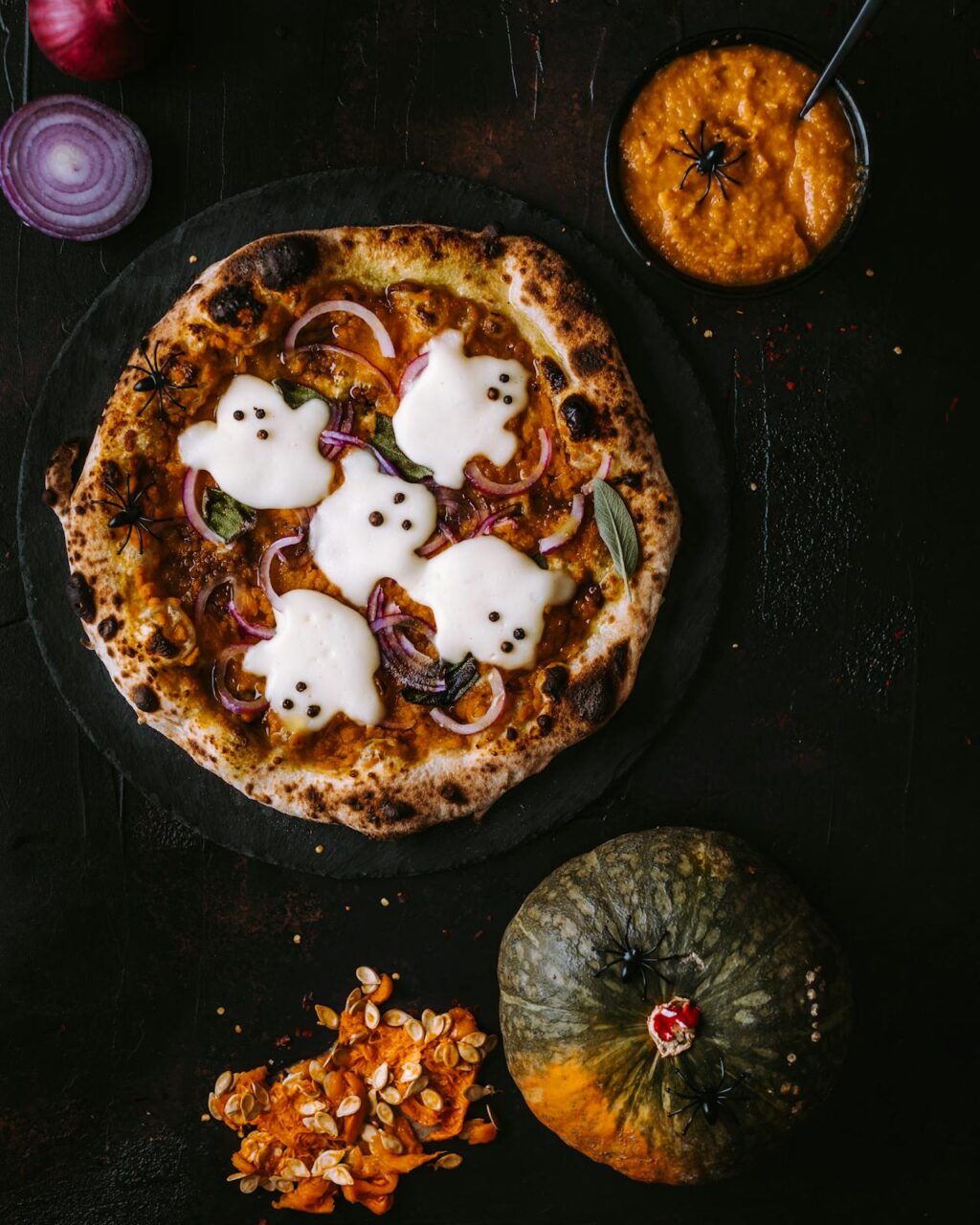 A pumpkin pizza with ghosts overlaid on the top