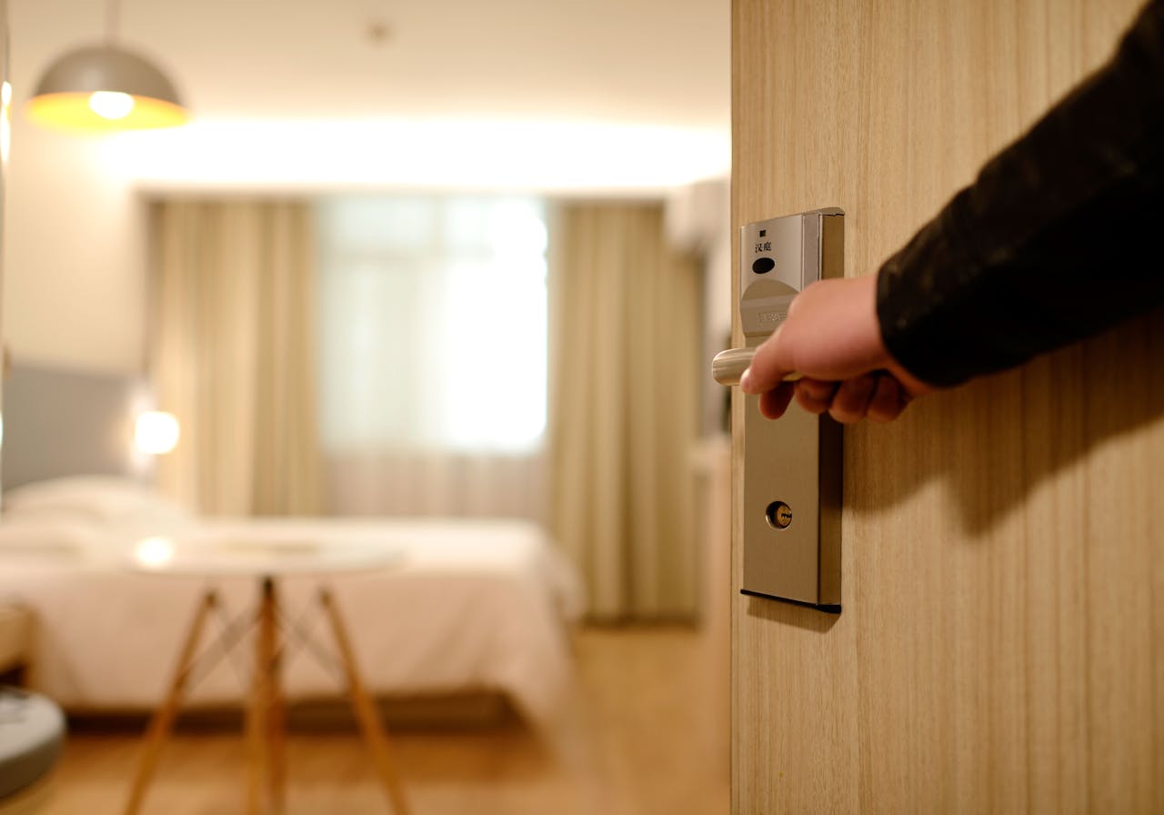 A man opening a door to expose an empty hotel room